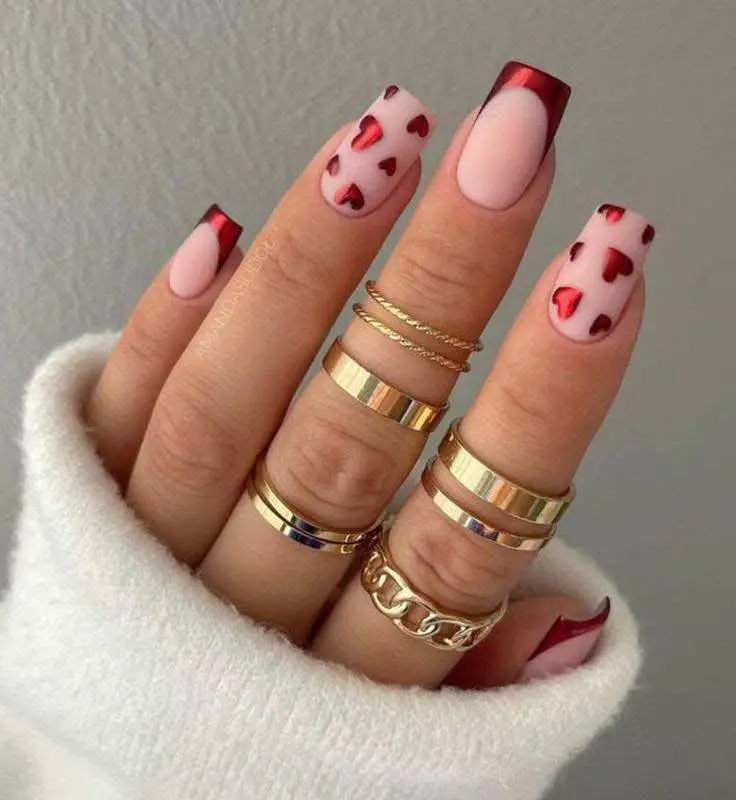 Square nails with metallic red French tips and red-and-pink checkered heart pattern.