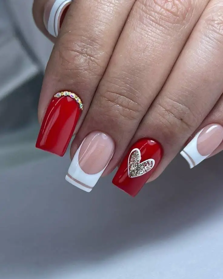 Red and white French manicure with crystal accents and a glitter heart.