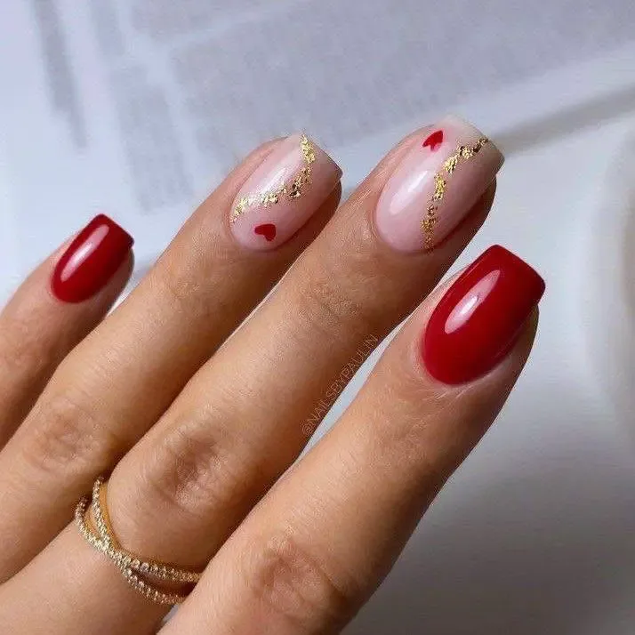 Oval nails with blush pink, red, and gold foil accents, including small hearts.