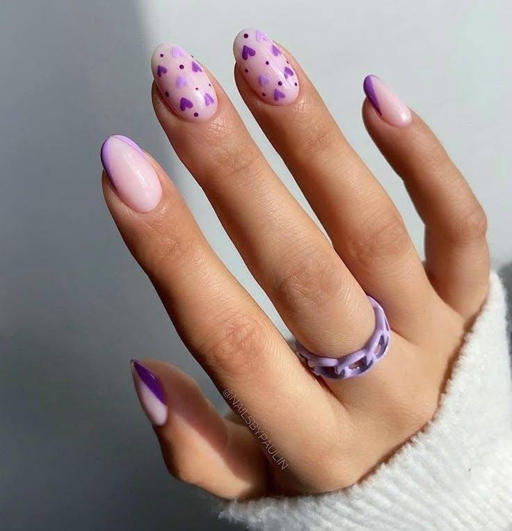 Round nails with light pink base and small purple hearts and purple French tips.