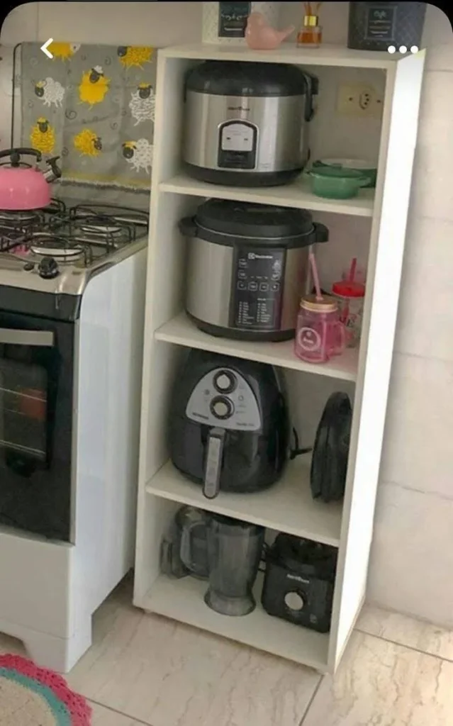 White kitchen cabinets and a separate shelving unit holding small appliances, creating a cohesive storage system.