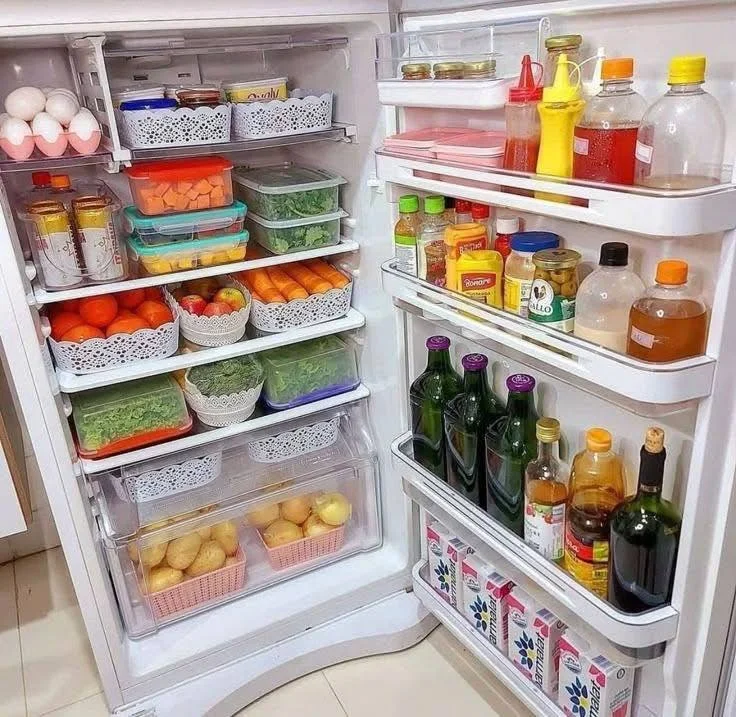 Refrigerator interior organized with clear, stackable containers and labeled bins.