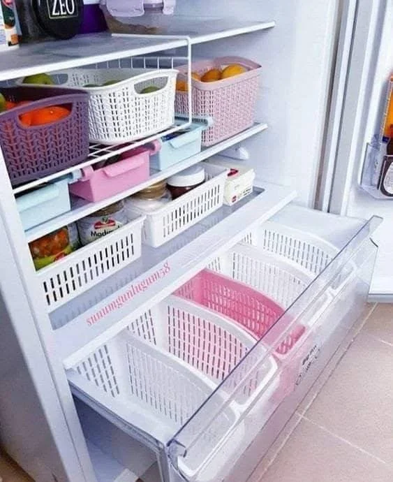 Refrigerator drawer organized with dividers and bins, separating various food items.