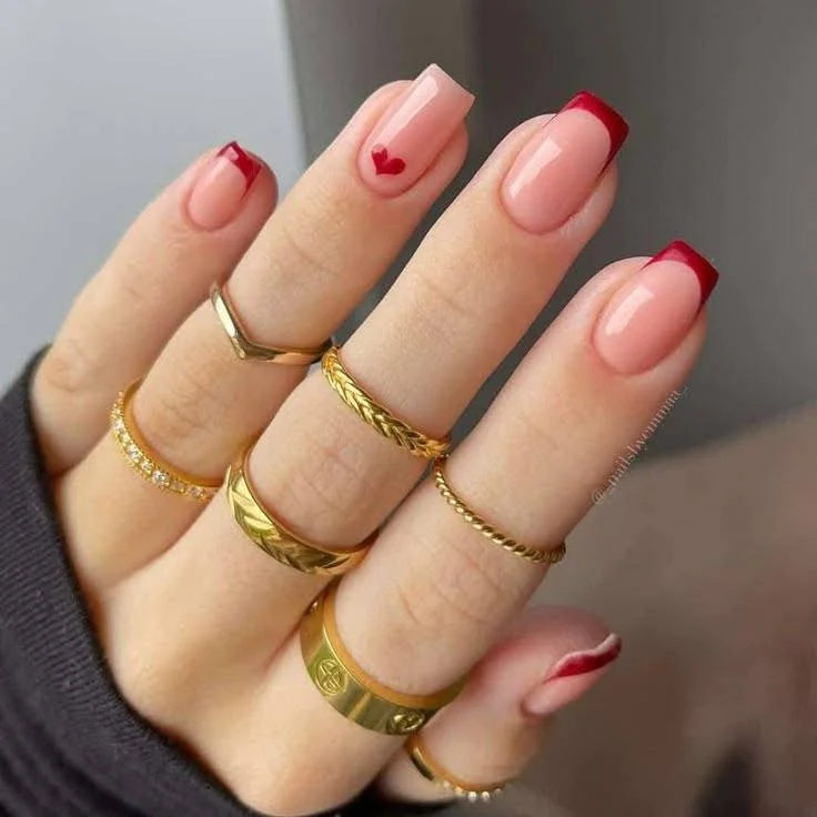 Short red wine nails with a nude accent nail featuring a glitter stripe, showcasing a glamorous and sophisticated look.