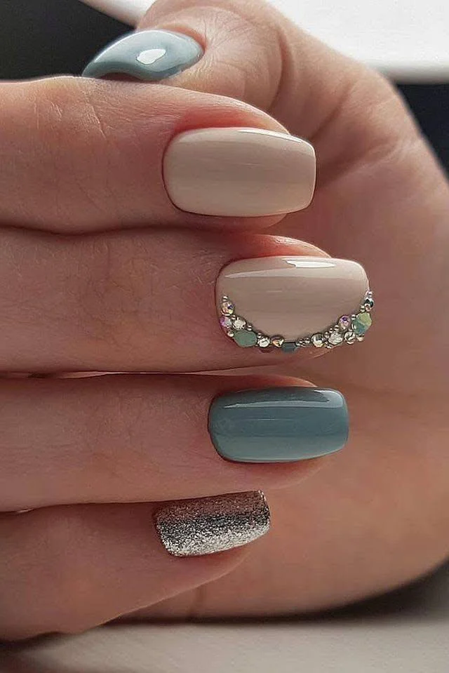 Short nails featuring muted teal, nude, and a rhinestone-accented nail, showcasing a glamorous and elegant design.