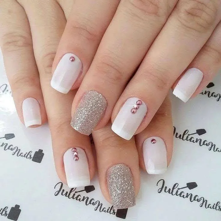 Short red nails with a glitter accent nail and rhinestone details, exhibiting a glamorous and luxurious style.