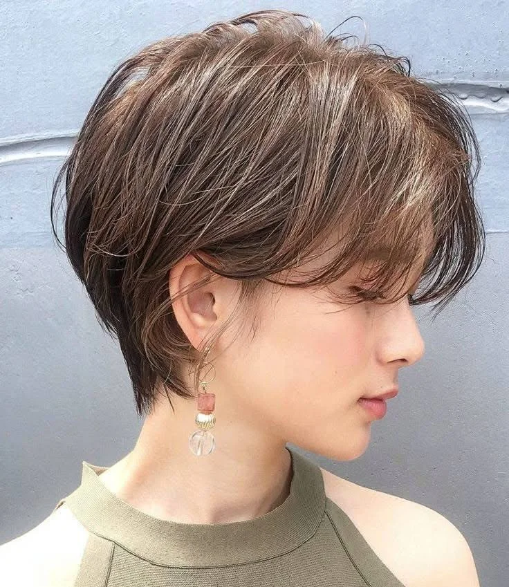 Textured pixie with long bangs, a stylish short haircut with a feminine touch for 2025.