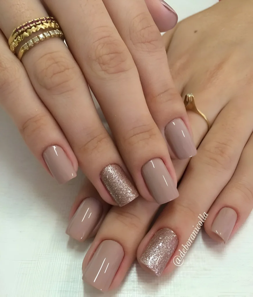 Short taupe nails with rose gold glitter accent nails.