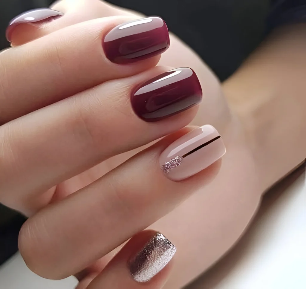 Short nails with deep red wine polish, a nude accent nail with a black line and silver glitter, and a full silver glitter nail.