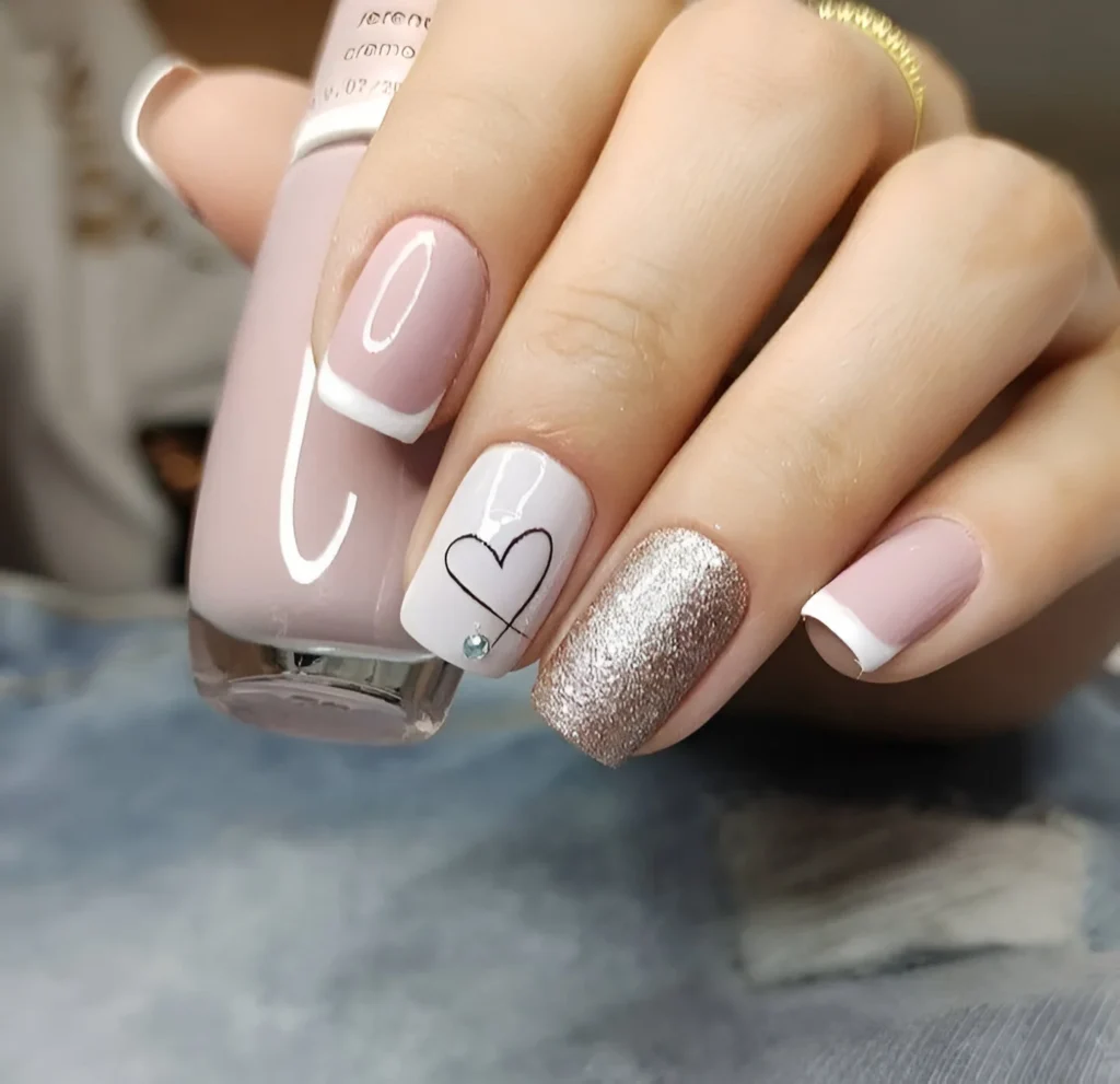 Short nails with nude and white polish, a heart outline design, white French tips, and a champagne glitter accent nail.