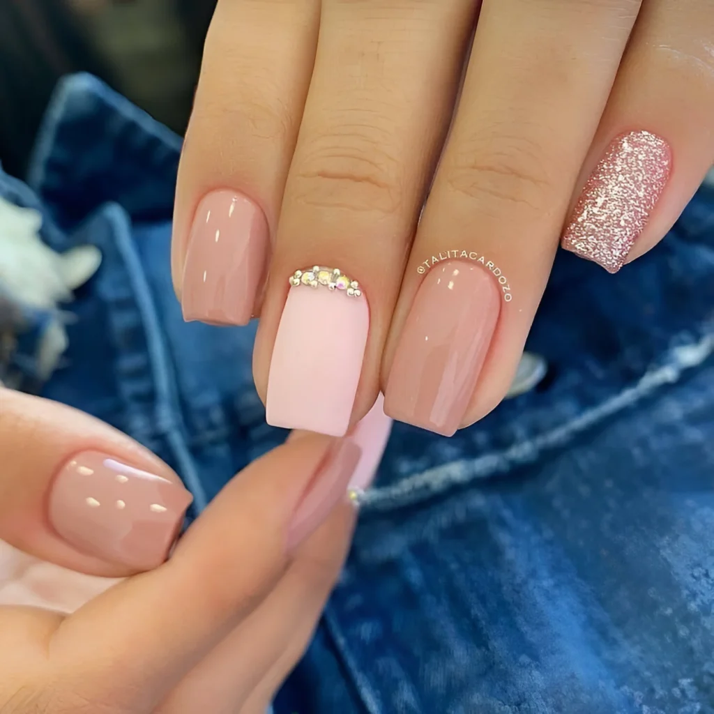 Short nails with rose and pale pink polish, rhinestone accents, and a pink glitter accent nail.