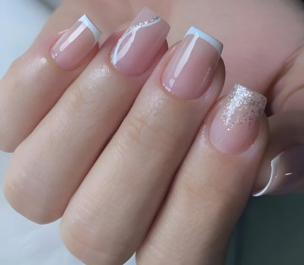 Short nails with a French manicure, a thin silver accent line, and a glitter accent nail.