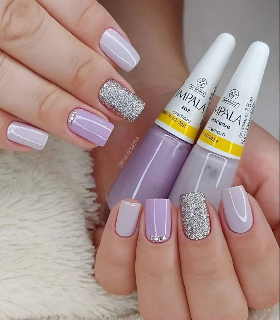 Short nails in various shades of lavender with rhinestone accents and a silver glitter accent nail.