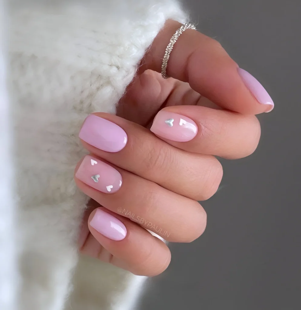 Simple pastel pink nail designs with small silver heart accents.