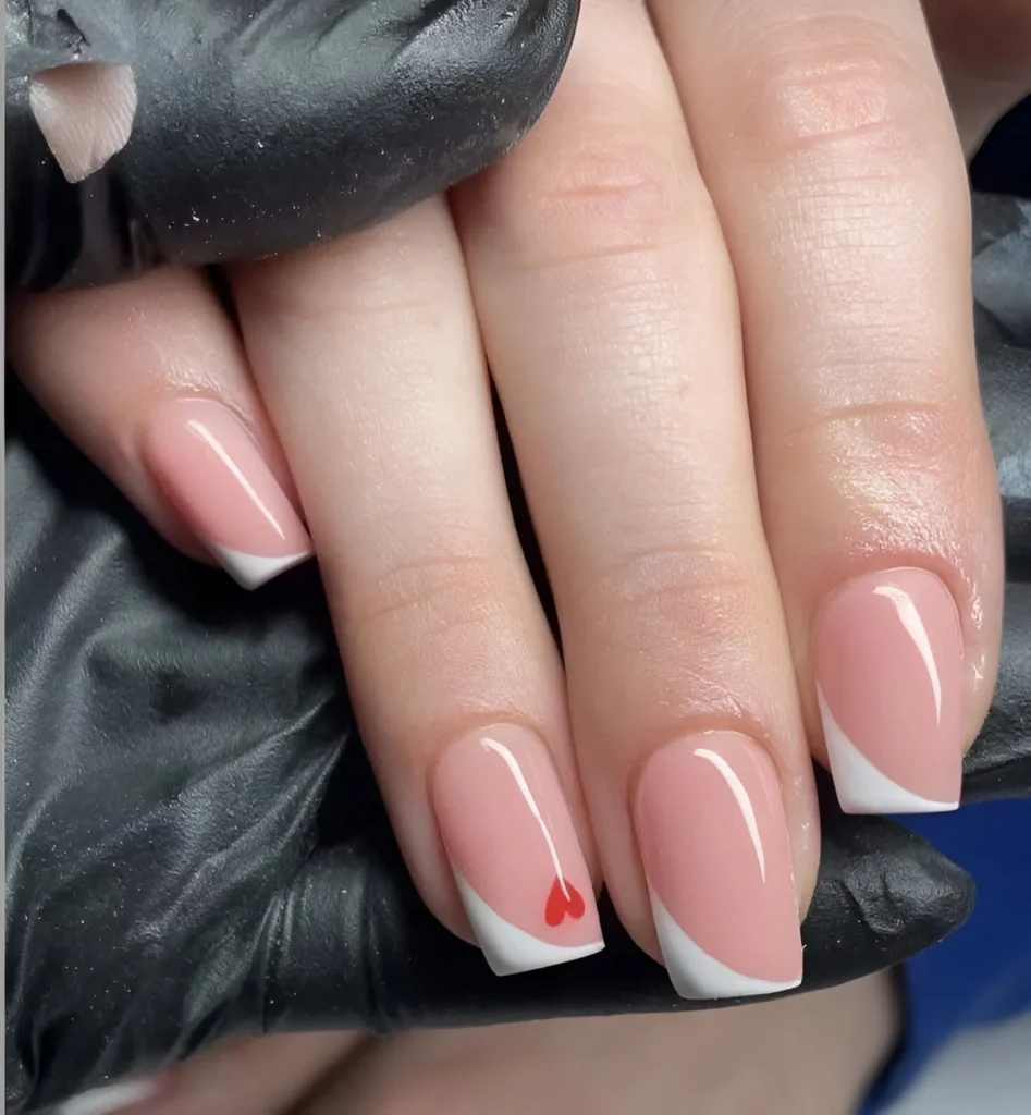 Simple nail designs with angled French manicure and red heart accent.