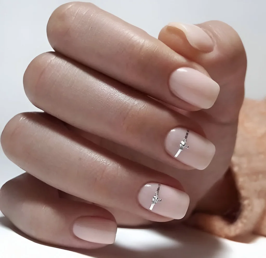 Simple nude nail designs with silver stripe and rhinestone accent.