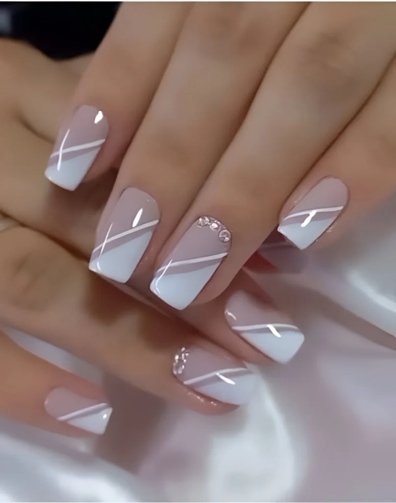 Simple nail designs with criss-cross white lines and rhinestone accents.