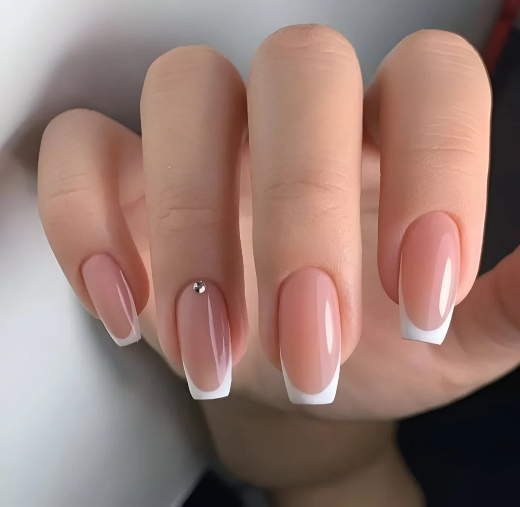 Simple, classic French manicure nail designs with a single rhinestone accent.