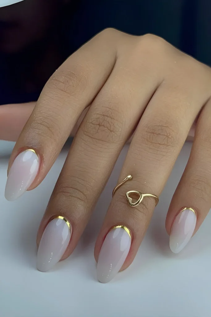 Simple nail designs with sheer white polish and gold cuticle detail.