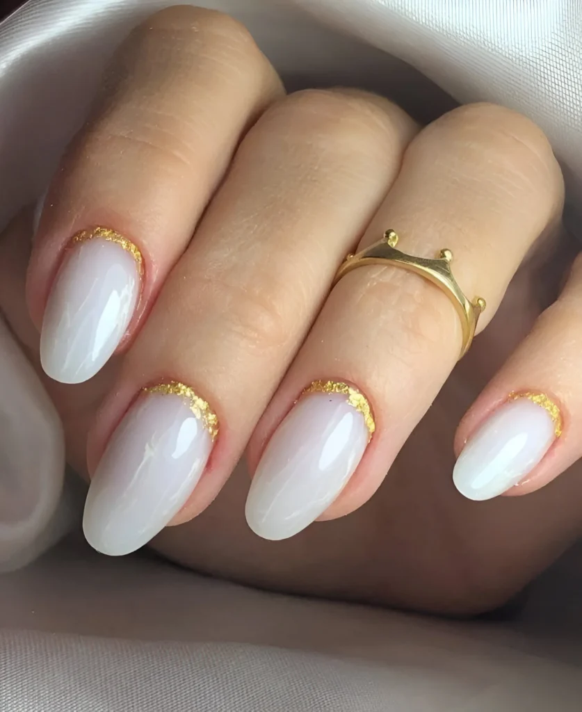 Simple nail designs with off-white polish and gold glitter tips.