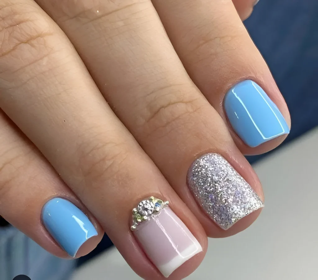 Sky blue nails with silver glitter and crystal accents.