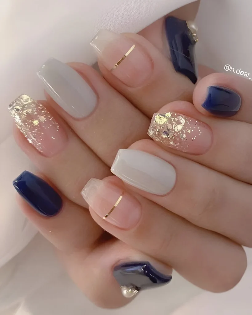 Navy, gray, and white nails with gold foil accents.