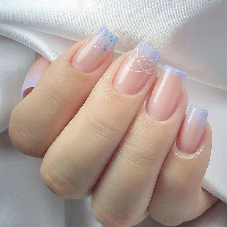 Elegant pastel lavender and white ombre nail design with delicate white swirls.