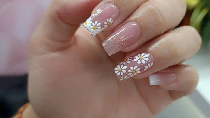 White daisy nail art with French tips and subtle glitter.