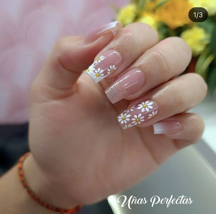 White daisy nail art with French tips and subtle glitter.