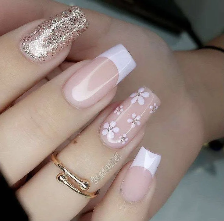 Pink and white flower nail art with French tips and glitter accent nail.