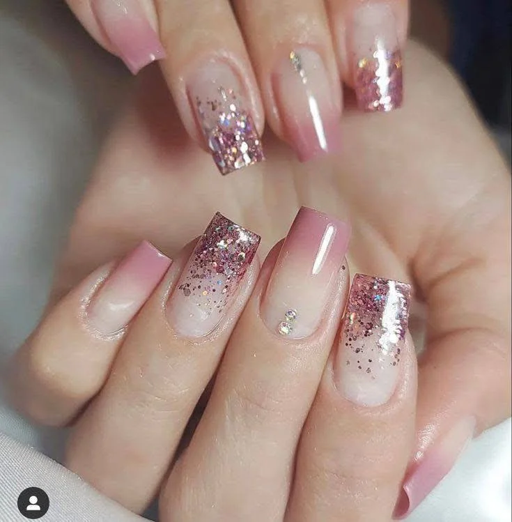 Pink glitter ombre nails with rhinestone accents.