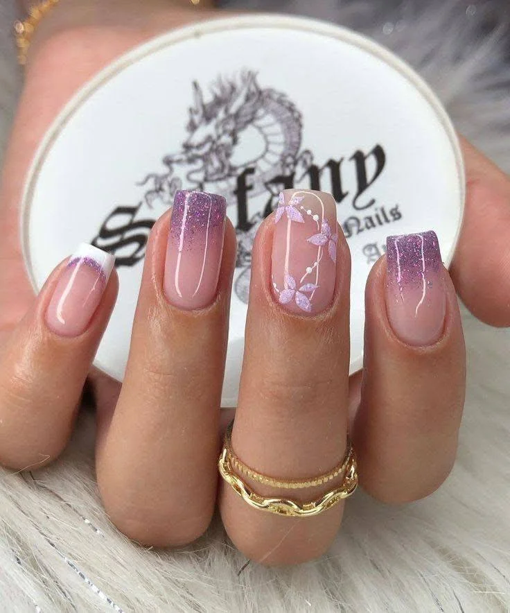 Lilac and white ombre nails with floral accent and glitter tips.