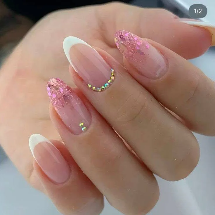 Classic French manicure with rhinestone and pink glitter accents.