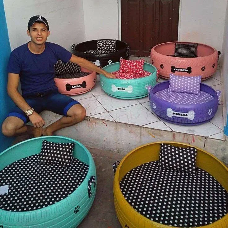 Man surrounded by several personalized upcycled tire pet beds, each with a different color and design. upcycling old tires