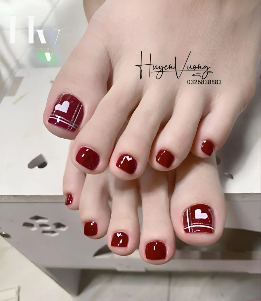 Red toe nail design with white heart accent, feminine and romantic pedicure.