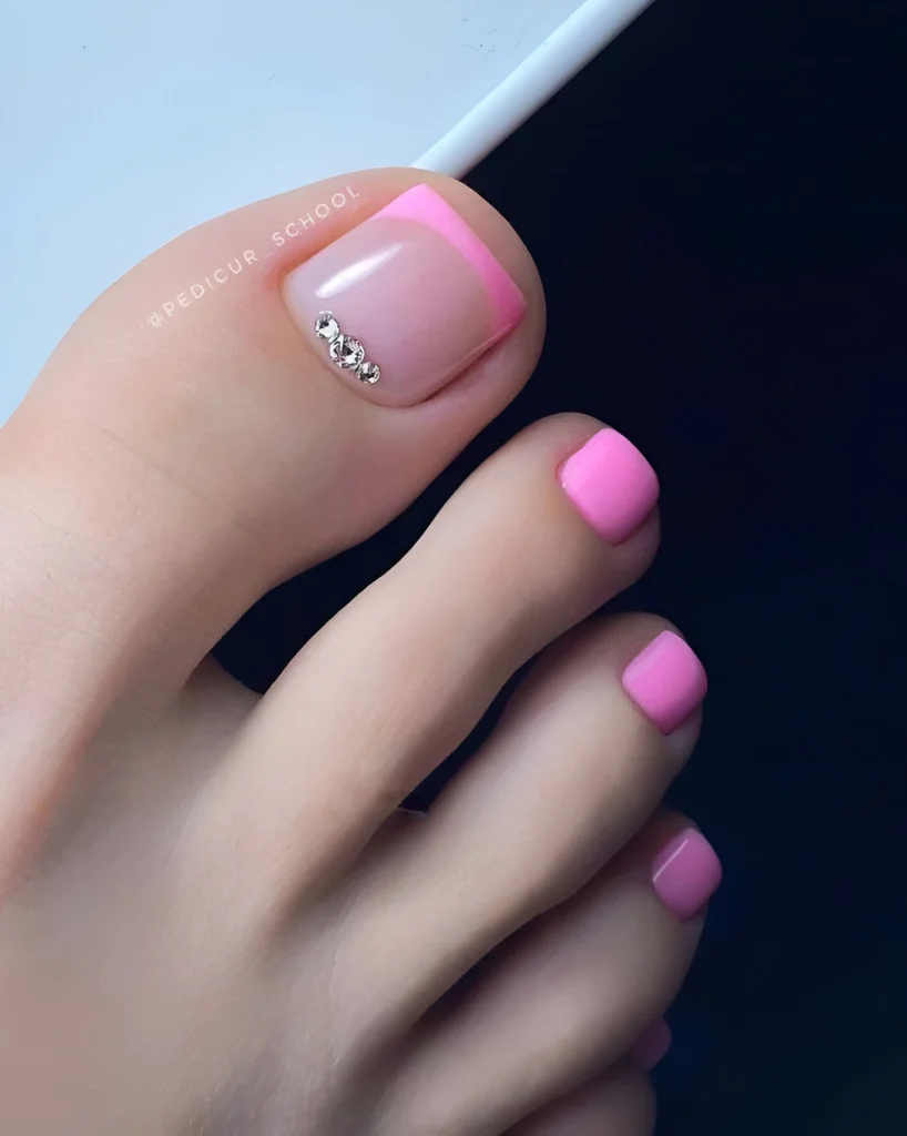 Pink French tip toe nail design with crystal accents, bright pedicure.