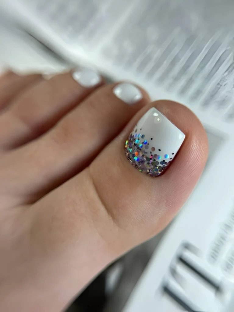 White toe nail design with multi-colored glitter fade on big toe, sparkly pedicure.