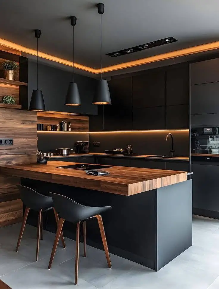 Black kitchen with a large wood-topped island, pendant lighting, and perimeter LED strip lighting.