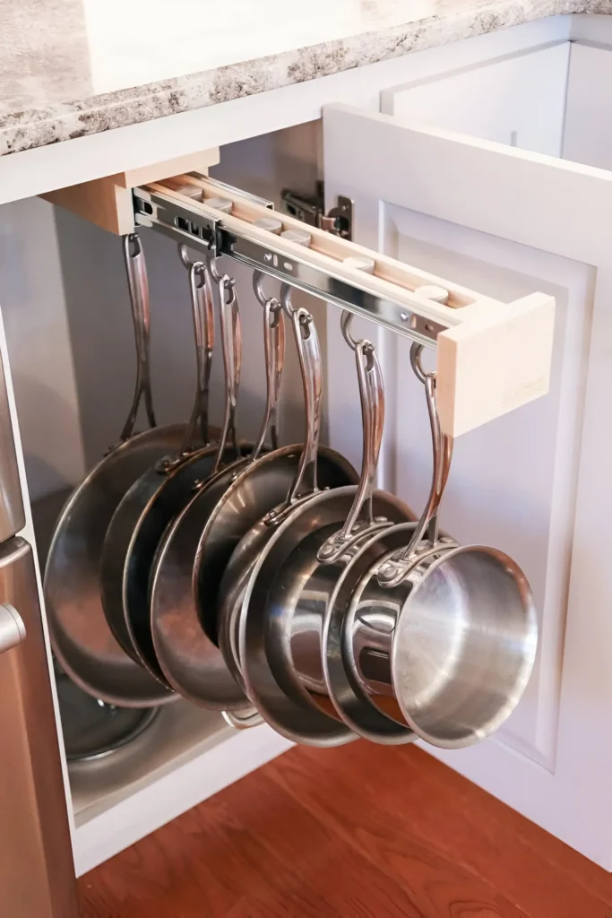 Pull-out rack for hanging pots and pans inside a kitchen cabinet.