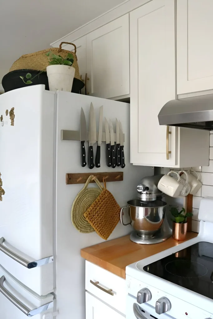 Magnetic knife rack mounted on the side of a refrigerator in a kitchen.