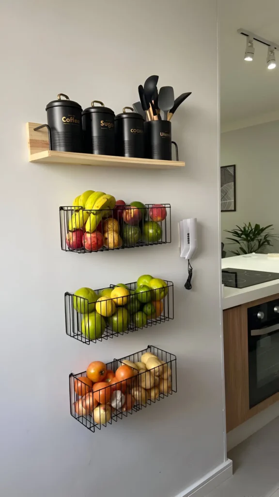 Kitchen wall with mounted wire baskets for produce and a shelf with labeled canisters. Brilliant Home Organization Ideas to Maximize Space