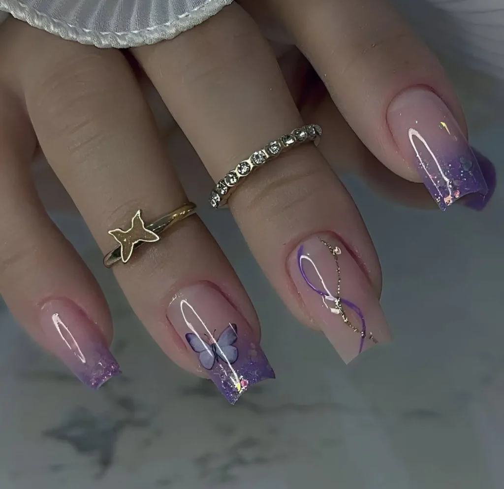 Square-shaped acrylic nails featuring a gradient of pale purple to clear, with glitter accents on the tips, delicate white and lilac swirls, and a 3D butterfly embellishment on one nail.