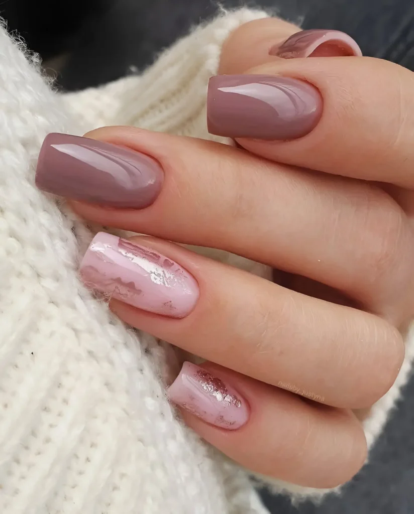 Square-shaped nails. Some are painted a solid, glossy dusty rose, while others feature a pale pink base with a marbled effect and irregular silver foil accents.