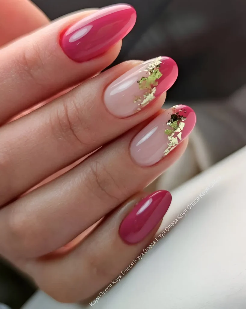 Oval-shaped nails. Some are painted a solid, glossy, bright pink. Others have a pale, nearly-clear pink base with irregular pieces of gold leaf applied to create an abstract design.