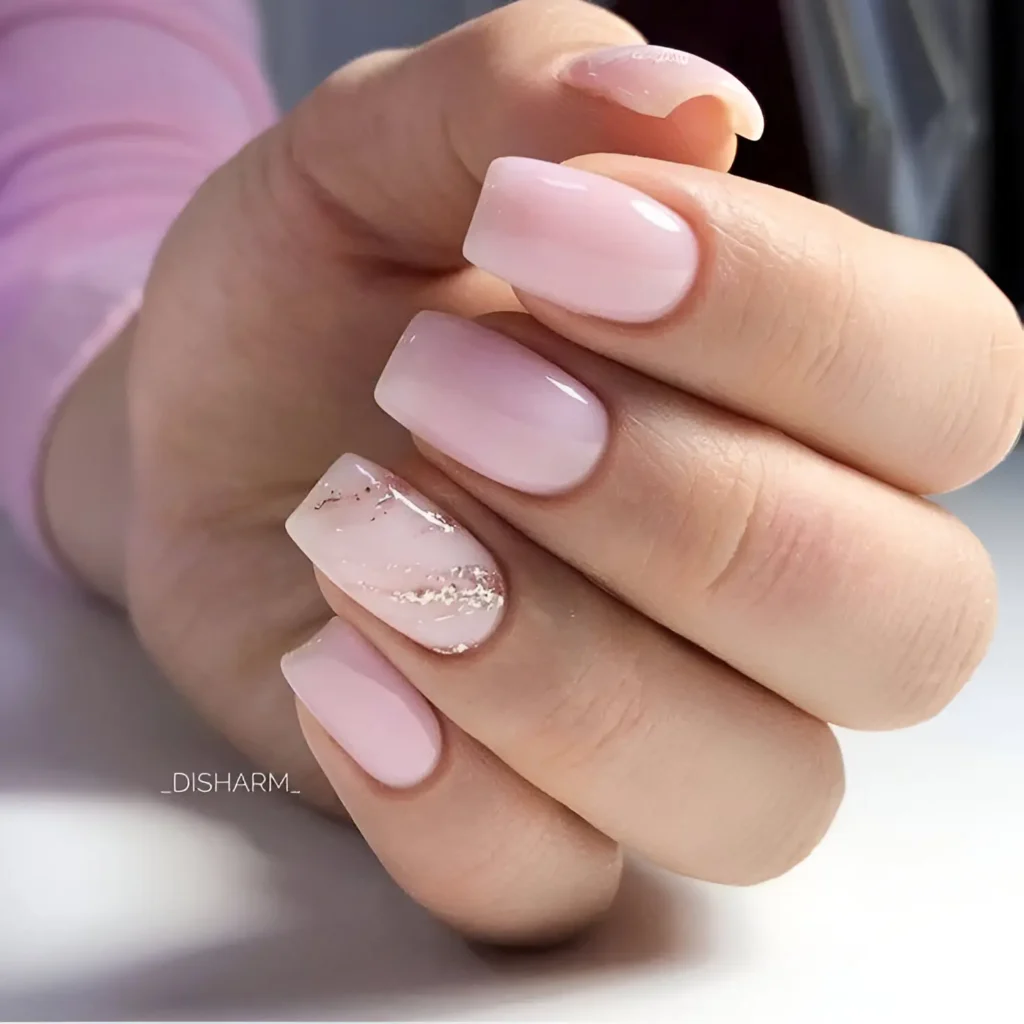 Short, square-shaped nails. Most are painted a solid, glossy, milky pink. One nail has a pale pink base with a very subtle marbled effect and small, irregularly shaped pieces of silver foil.