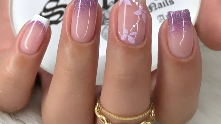 Square-shaped nails with multiple designs. One nail has a classic French tip, two have a gradient from clear at the base to lavender glitter at the tip, and one features hand-painted lavender flowers and leaves on a clear base.