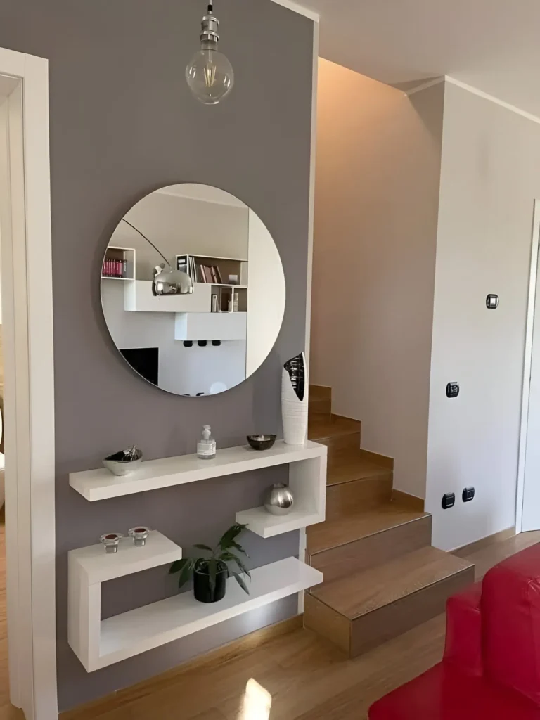 Contemporary entryway with floating shelves, a round mirror, and minimalist decor.