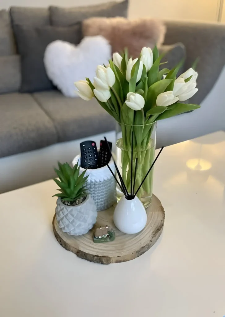 Coffee table with fresh tulips, greenery, and decorative accents on a wooden tray.