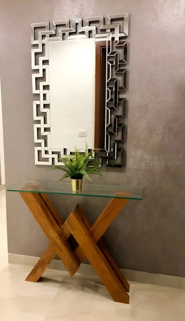 Elegant entryway featuring a geometric framed mirror and a glass console table with a sculptural wooden base. Interior Design Tips