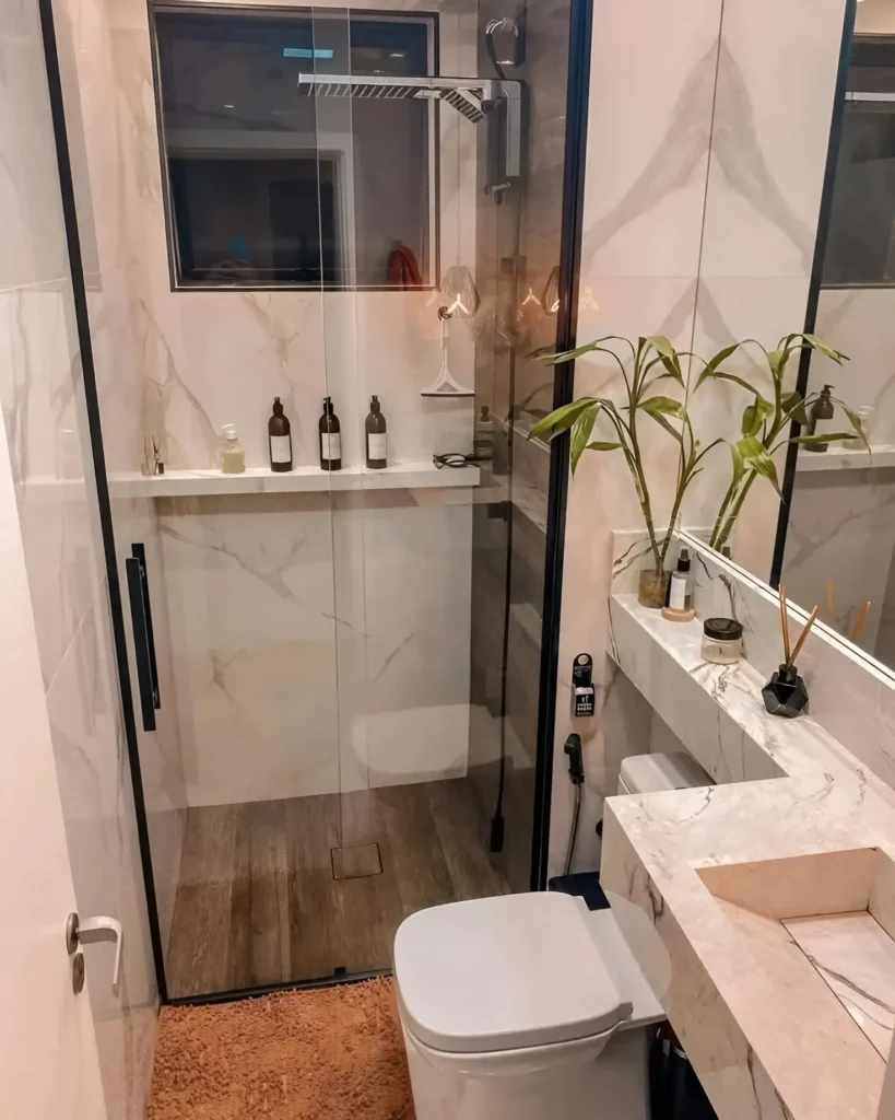 Modern small bathroom with marble-look walls and vanity, black shower frame, and integrated sink.